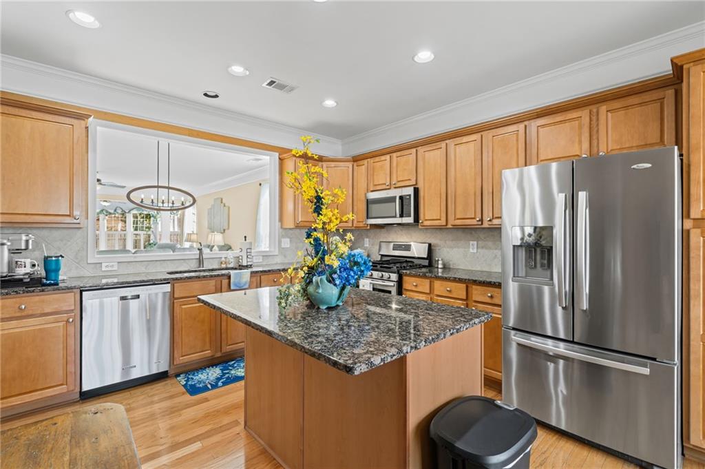 4945 Kings Common Way Cumming, GA 30040 - Photo 13 of 40 a kitchen with stainless steel appliances granite countertop a refrigerator a sink dishwasher a stove and white countertops with wooden floor
