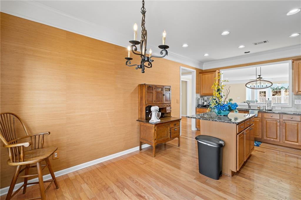 4945 Kings Common Way Cumming, GA 30040 - Photo 16 of 40 a kitchen with stainless steel appliances granite countertop a stove a sink dishwasher and a dining table with wooden floor
