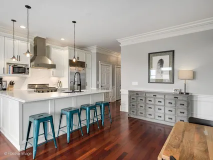 a kitchen with stainless steel appliances a stove a sink a center island and a wooden floor