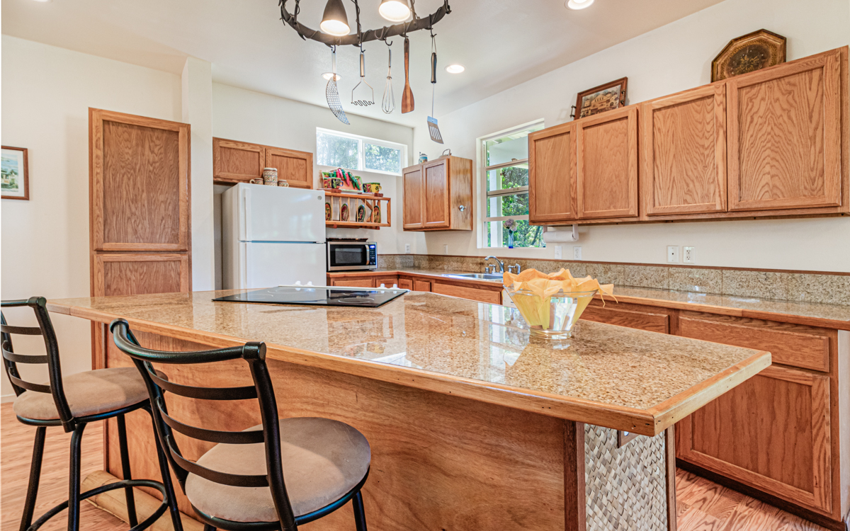 99-1846 Painiu Loop Volcano, HI 96785 - Photo 4 of 30 a kitchen with a dining table chairs and refrigerator