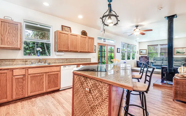 a very nice looking kitchen with granite countertop a stove two sinks and a dishwasher with wooden floor