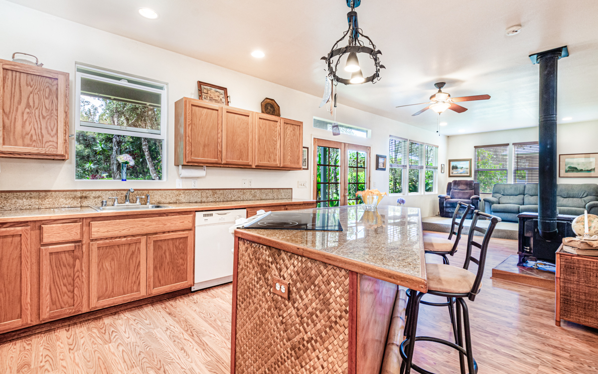 99-1846 Painiu Loop Volcano, HI 96785 - Photo 6 of 30 a very nice looking kitchen with granite countertop a stove two sinks and a dishwasher with wooden floor