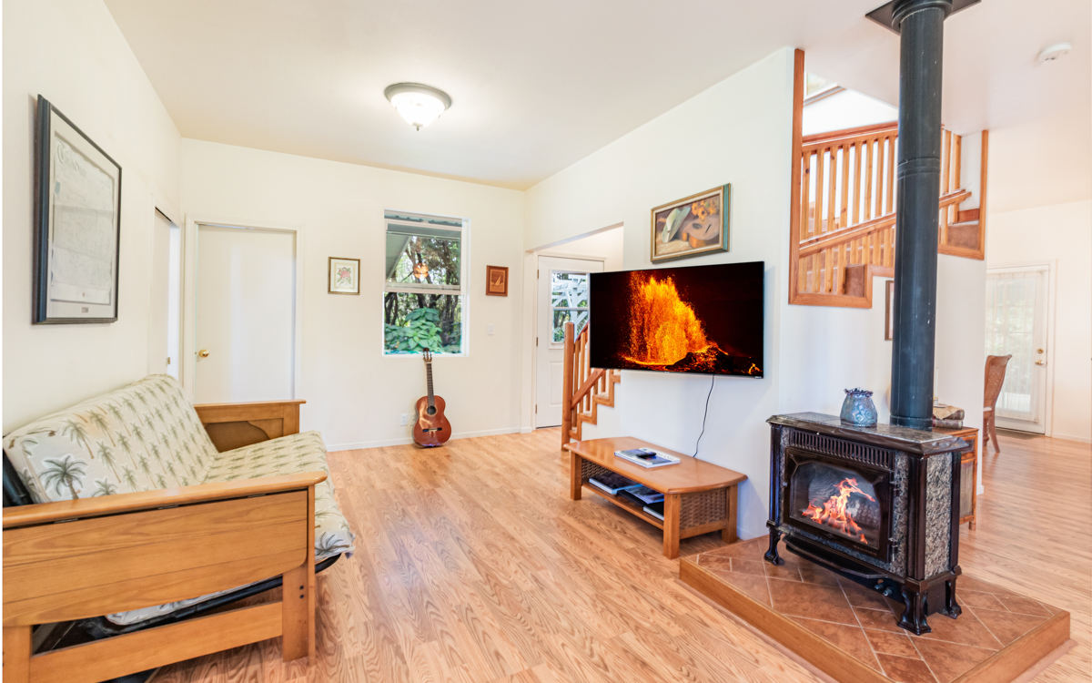 99-1846 Painiu Loop Volcano, HI 96785 - Photo 8 of 30 a living room with furniture a flat screen tv and a fireplace
