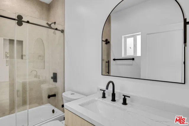 a bathroom with a sink and mirror with bathtub