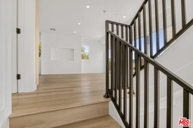 a view of staircase with wooden floor and white walls