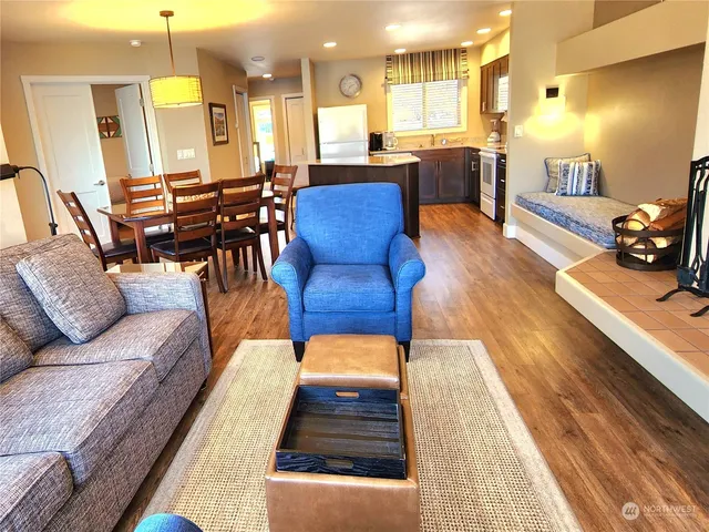 a living room with furniture kitchen view and a wooden floor