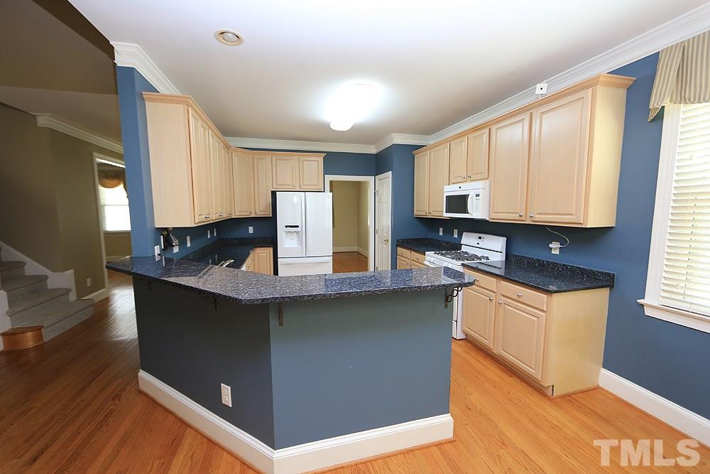 8203 Kitzel Way Raleigh, NC 27615 - Photo 4 of 14 a kitchen with stainless steel appliances granite countertop a stove a sink a refrigerator a microwave oven with wooden cabinets and floor