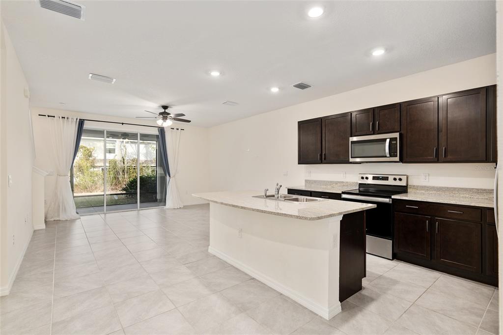 13818 Northwest 9th Road Newberry, FL 32669 - Photo 32 of 56 a kitchen with stainless steel appliances granite countertop a stove top oven a sink and a refrigerator