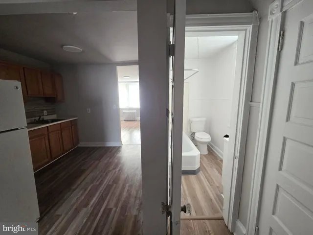 a view of a kitchen from the hallway with a wooden floor