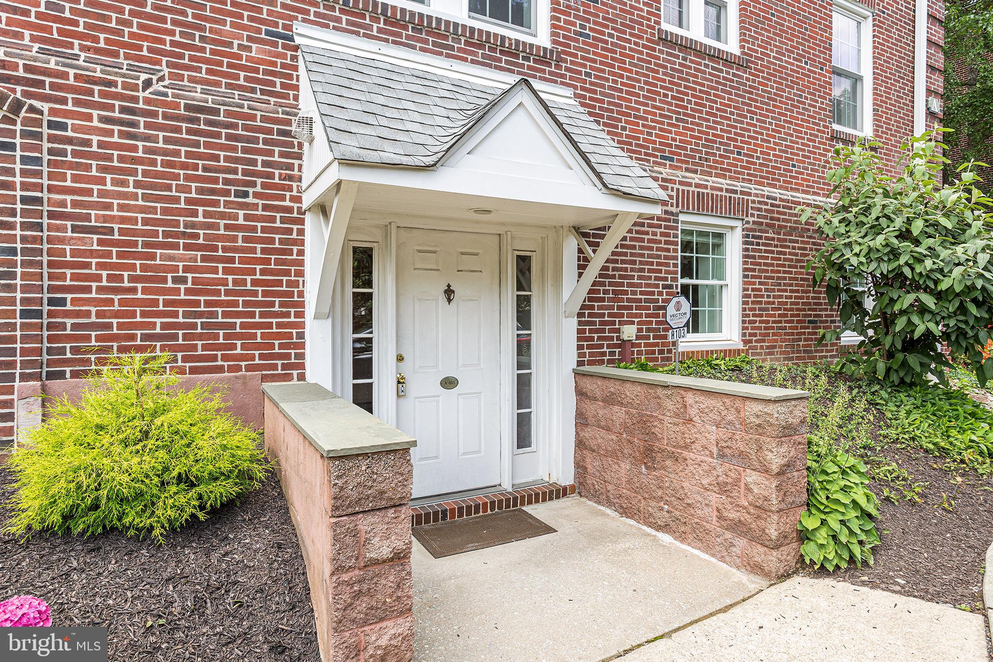 104 Woodside Road, Unit A103 Haverford, PA 19041 - Photo 1 of 2 a view of a wooden door with a chair and flower pot