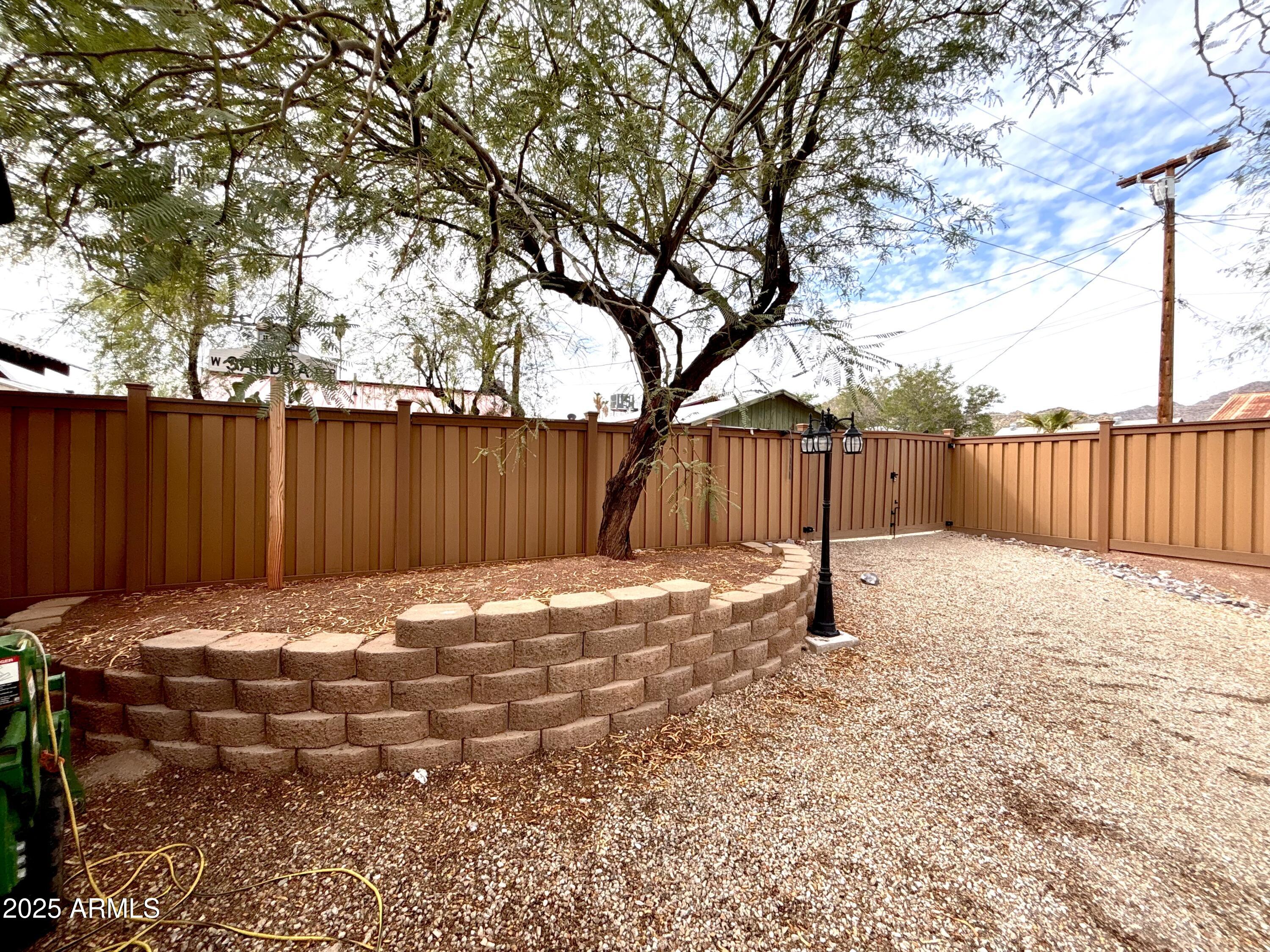 311 Solana Avenue Ajo, AZ 85321 - Photo 20 of 22 a view of a backyard with wooden fence and a large tree