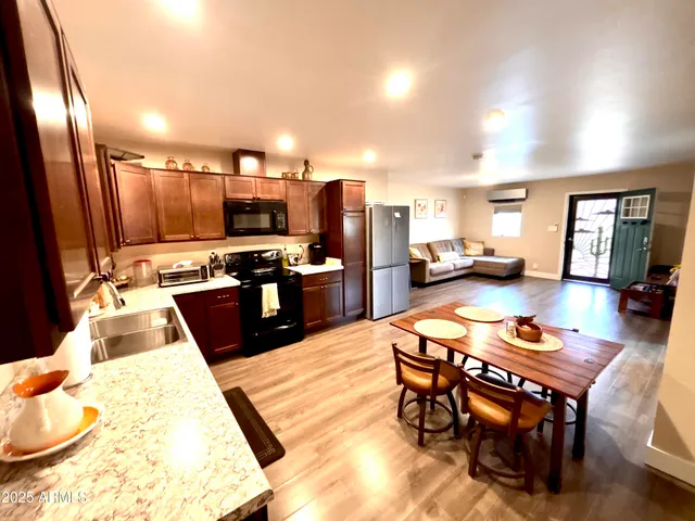 a kitchen with stainless steel appliances granite countertop a stove a refrigerator a sink a dining table and chairs with wooden floor