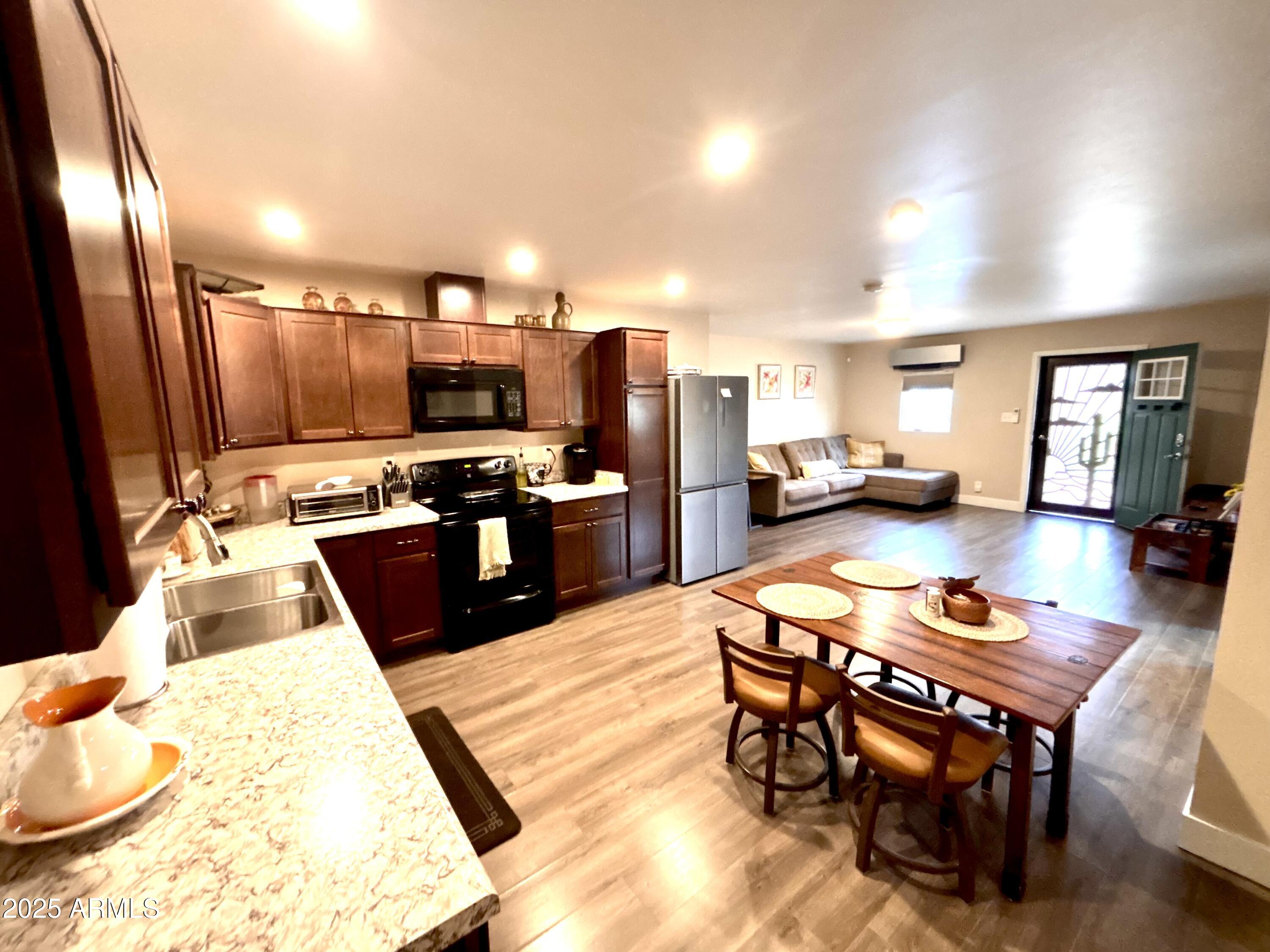 311 Solana Avenue Ajo, AZ 85321 - Photo 3 of 22 a kitchen with stainless steel appliances granite countertop a stove a refrigerator a sink a dining table and chairs with wooden floor