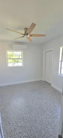 an empty room with windows and ceiling fan