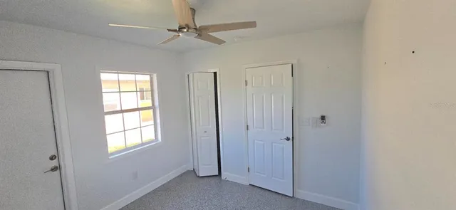 a view of empty room with window and ceiling fan