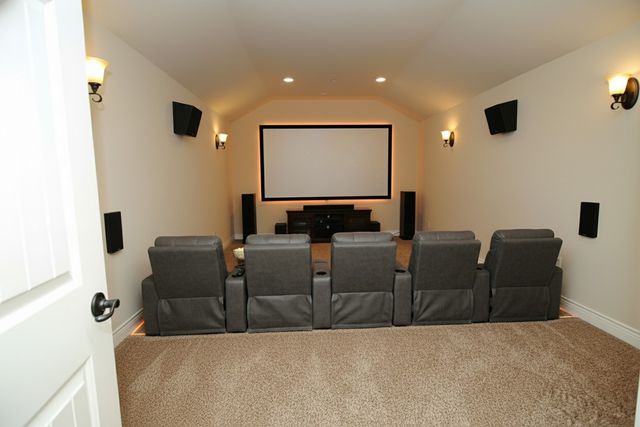 a living room with couches and projector with a flat screen tv