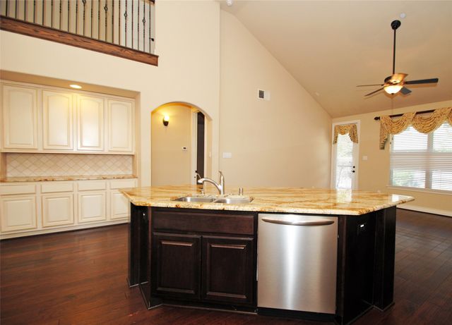 a kitchen with stainless steel appliances granite countertop a sink a stove and a wooden floor