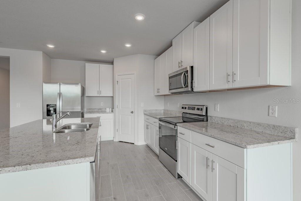 7041 Feather River Place Parrish, FL 34219 - Photo 11 of 32 a kitchen with stainless steel appliances granite countertop a sink a stove and a refrigerator