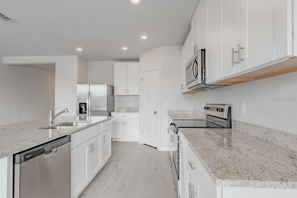 7041 Feather River Place Parrish, FL 34219 - Photo 13 of 32 a kitchen with stainless steel appliances granite countertop a sink stove and cabinets