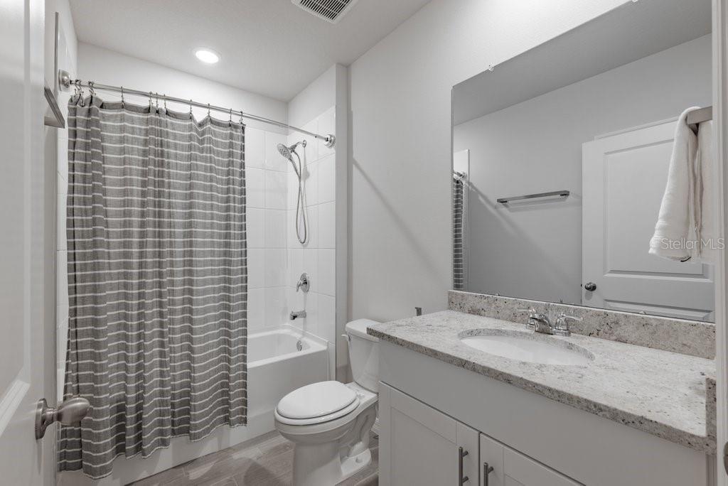 7041 Feather River Place Parrish, FL 34219 - Photo 20 of 32 a bathroom with a granite countertop sink toilet and shower