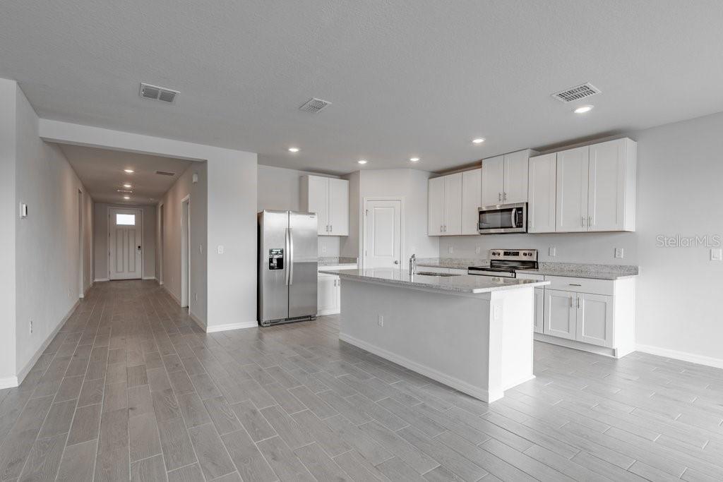 7041 Feather River Place Parrish, FL 34219 - Photo 9 of 32 a kitchen with stainless steel appliances a refrigerator sink and white cabinets