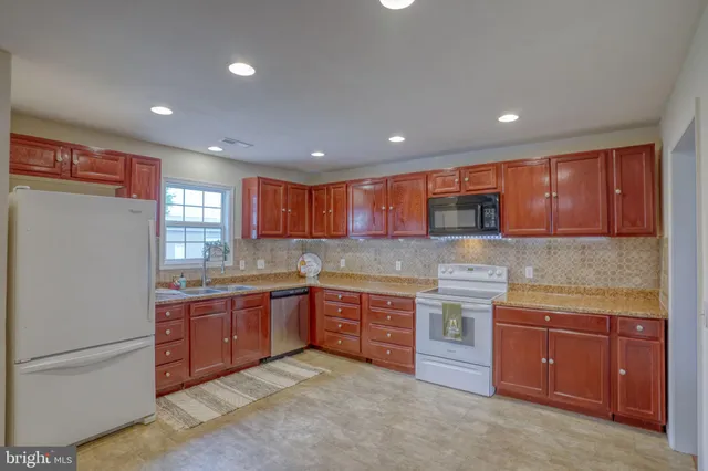 a kitchen with stainless steel appliances granite countertop wooden cabinets a stove top oven a sink and dishwasher