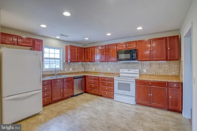 a kitchen with stainless steel appliances granite countertop wooden cabinets and a stove top oven