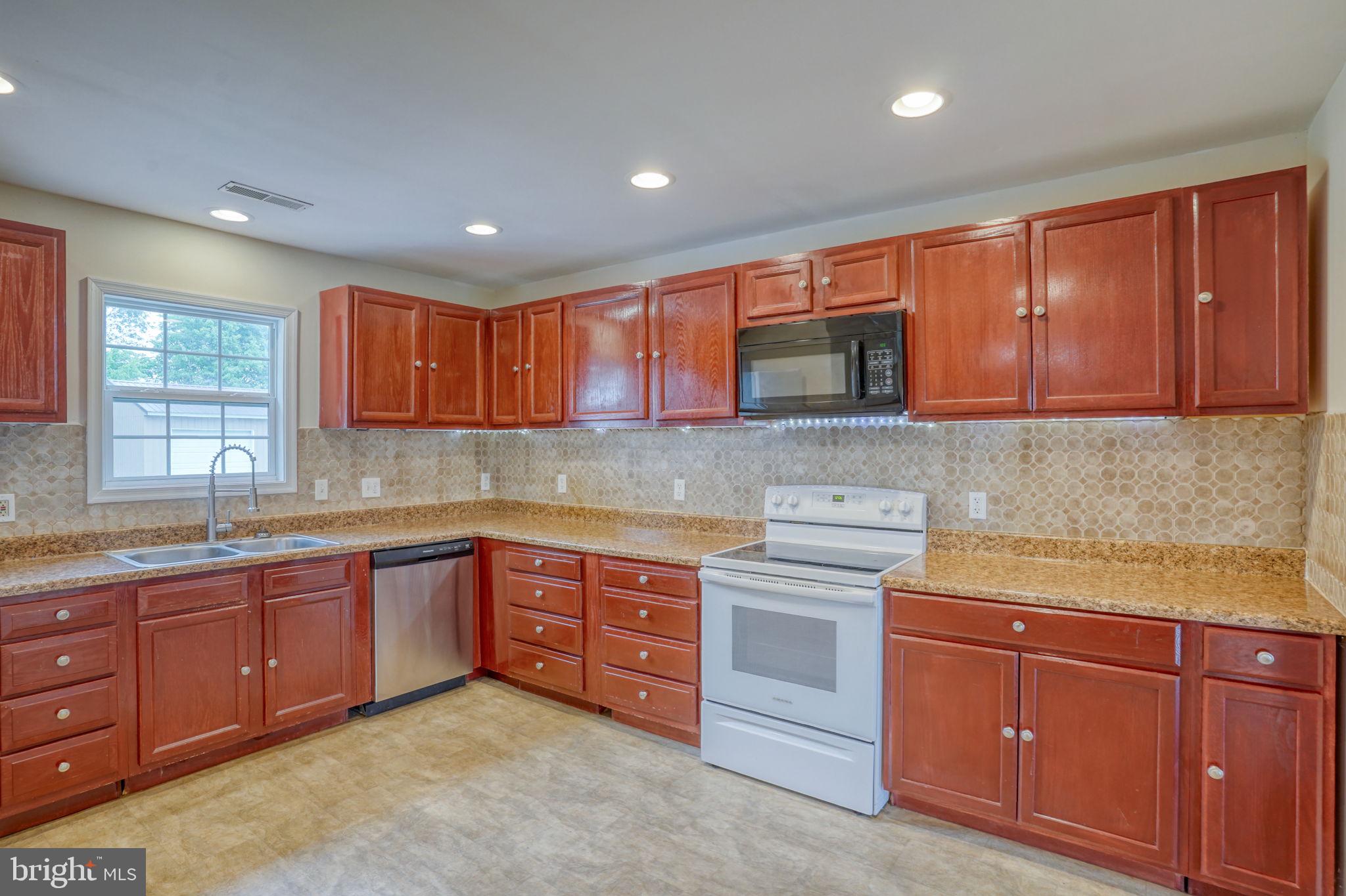 5926 Mt Holly Road East New Market, MD 21631 - Photo 21 of 36 a kitchen with stainless steel appliances granite countertop wooden cabinets and a stove top oven