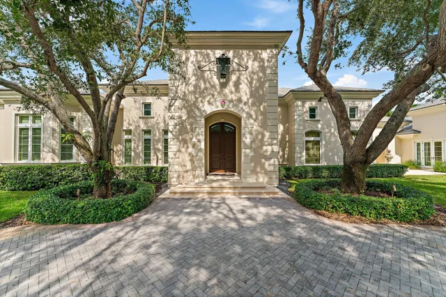 a front view of a house with garden and trees