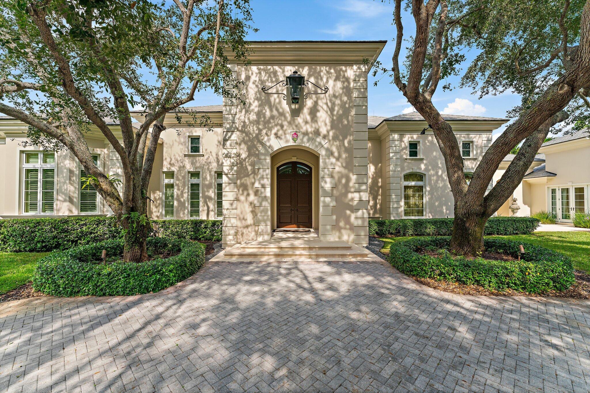 124 Bears Club Drive Jupiter, FL 33477 - Photo 13 of 22 a front view of a house with garden and trees
