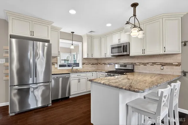 a kitchen with stainless steel appliances granite countertop a refrigerator a stove a sink dishwasher and a refrigerator with wooden floor