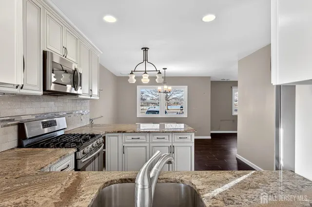 a kitchen with stainless steel appliances granite countertop a sink a stove a refrigerator cabinets and living room view