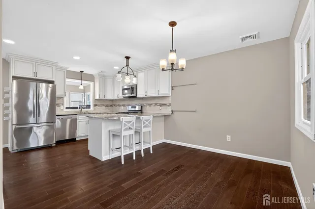 a kitchen with kitchen island white cabinets stainless steel appliances and wooden floor