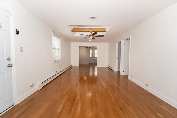 a view of an empty room with wooden floor and a window