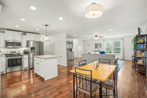 a kitchen with kitchen island granite countertop a refrigerator stove and wooden floor