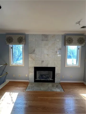 an empty room with wooden floor a fireplace and windows