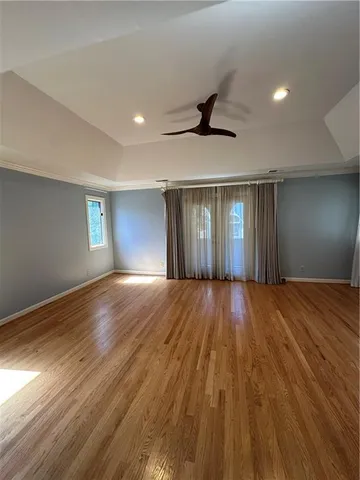a view of an empty room with window and wooden floor