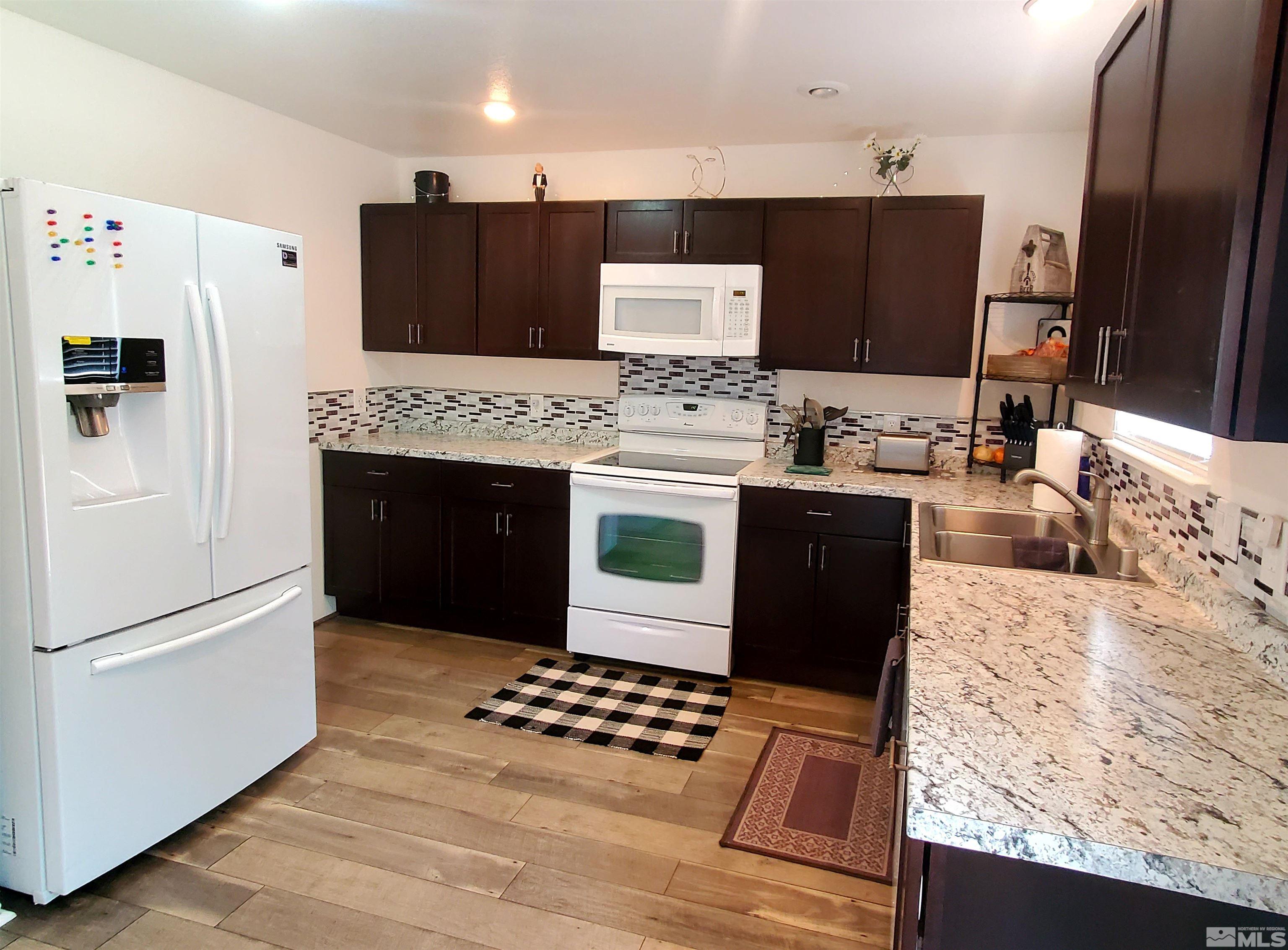 13590 Mt Olympus Street Reno, NV 89506 - Photo 2 of 17 a kitchen with stainless steel appliances kitchen island granite countertop a refrigerator stove and sink