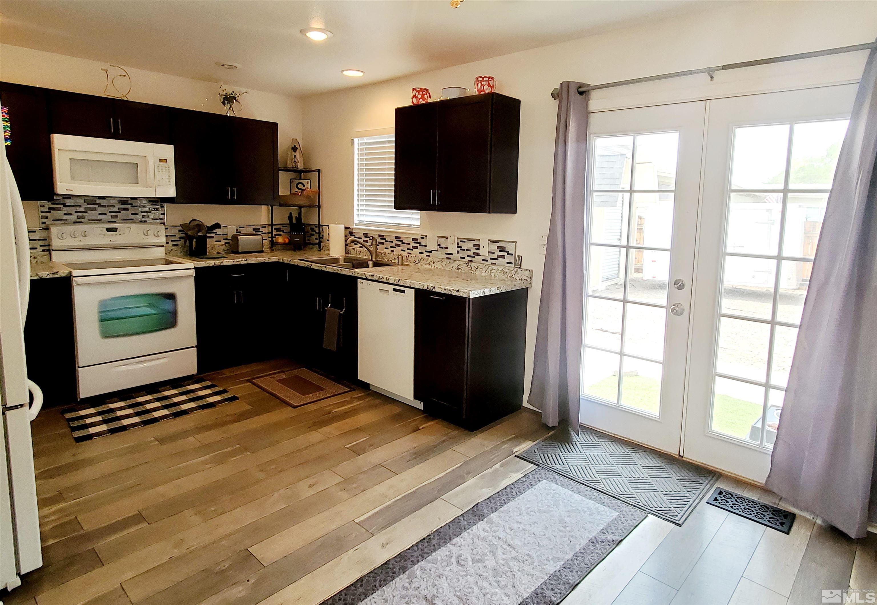 13590 Mt Olympus Street Reno, NV 89506 - Photo 3 of 17 a kitchen with stainless steel appliances kitchen island granite countertop a stove top oven and sink