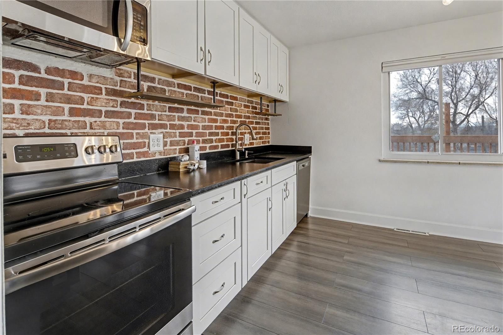 9142 Oberon Road Arvada, CO 80004 - Photo 2 of 35 a kitchen with granite countertop a stove and a sink