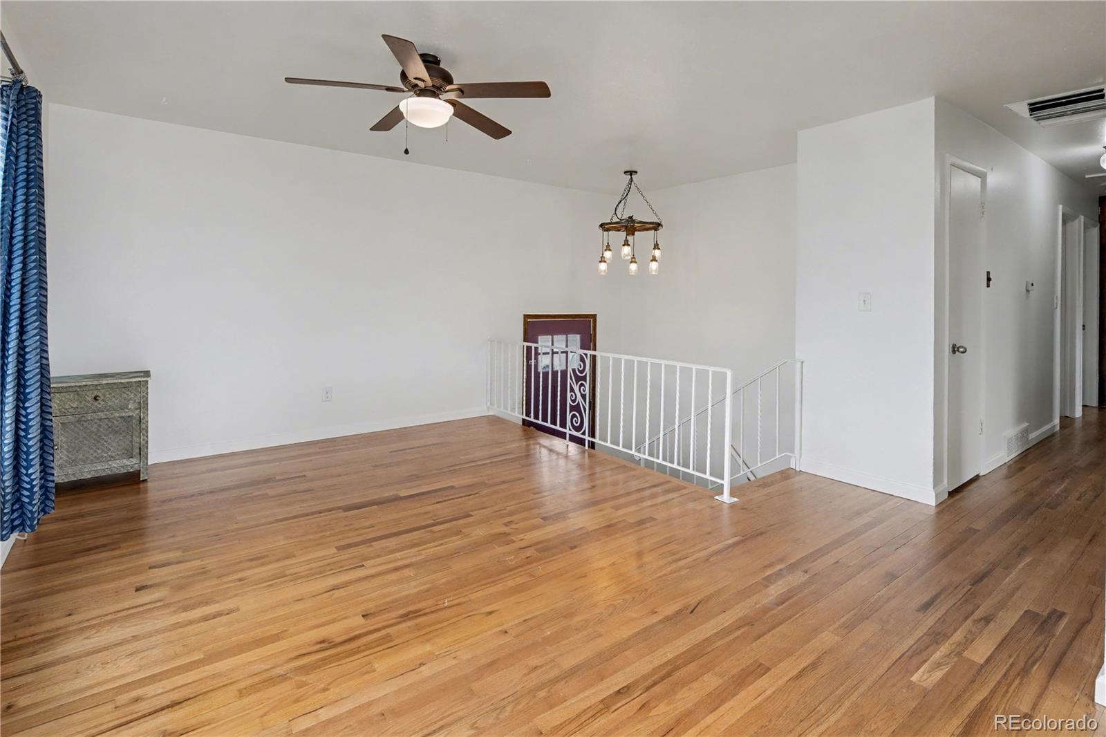 9142 Oberon Road Arvada, CO 80004 - Photo 7 of 35 a view of an empty room with wooden floor and a ceiling fan