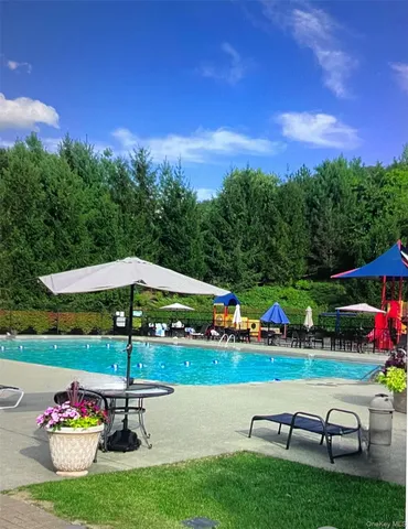 a view of a table and chairs under an umbrella in front of house