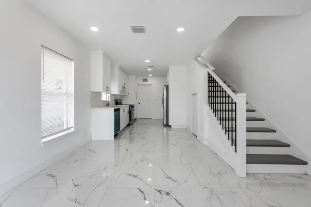 an entryway in a hall with a window and refrigerator
