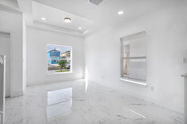 an empty room with windows and painting on the wall