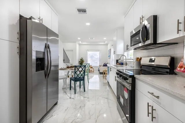 a kitchen with stainless steel appliances granite countertop white cabinets a sink and a stove