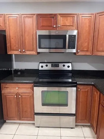 a kitchen with granite countertop a stove top oven microwave and cabinets