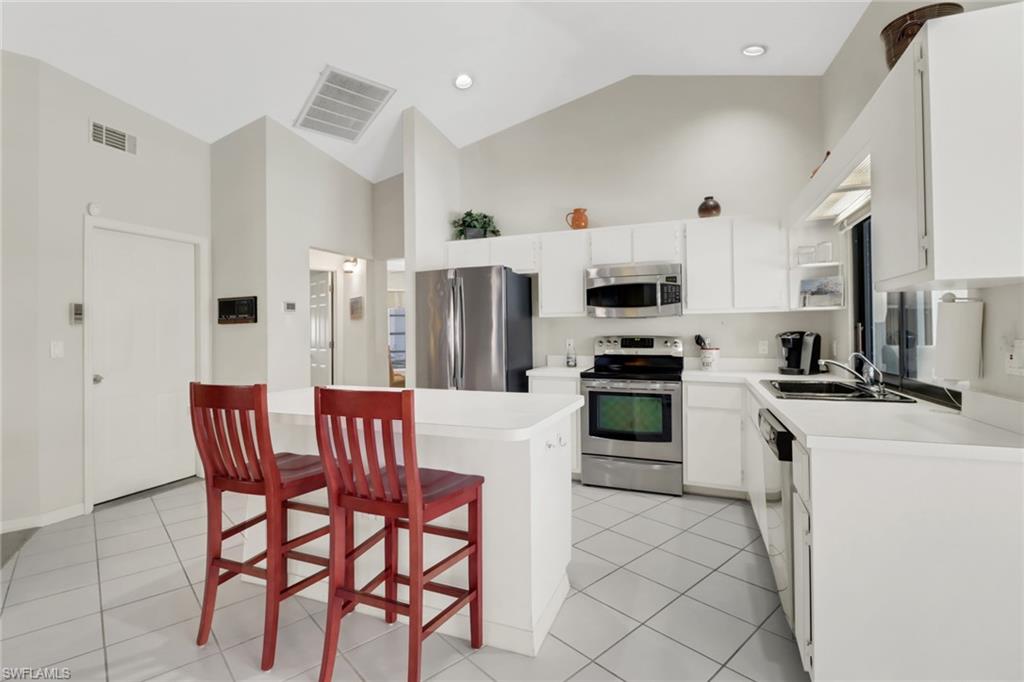 4961 Berkeley Drive Naples, FL 34112 - Photo 3 of 29 a kitchen with stainless steel appliances kitchen island granite countertop a table and chairs