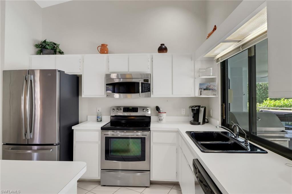 4961 Berkeley Drive Naples, FL 34112 - Photo 4 of 29 a kitchen with stainless steel appliances a stove a sink a microwave and cabinets
