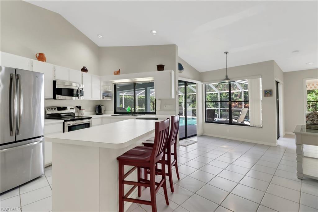 4961 Berkeley Drive Naples, FL 34112 - Photo 5 of 29 a kitchen with stainless steel appliances a refrigerator a stove a sink a dining table and chairs