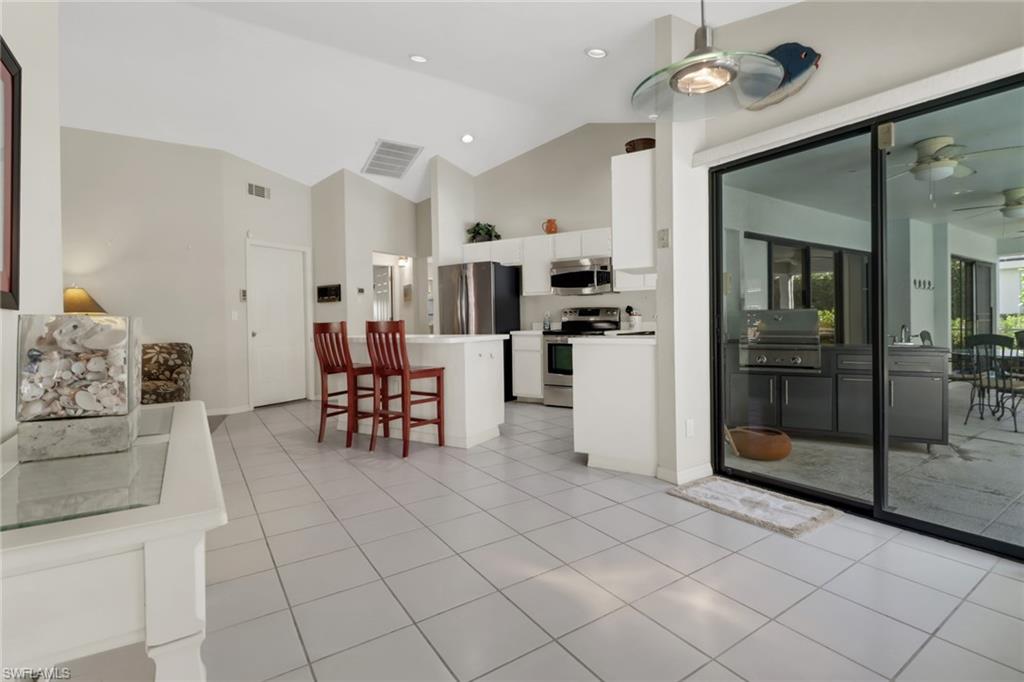 4961 Berkeley Drive Naples, FL 34112 - Photo 6 of 29 a kitchen with stainless steel appliances kitchen island granite countertop a refrigerator and a stove top oven